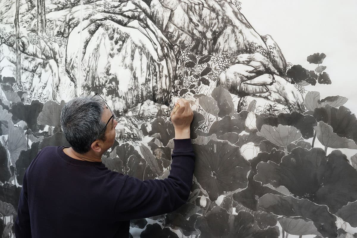 An artist paints in a small section of an intricate artwork.