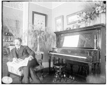 A man sitting in a chair by the Fischer piano in a house