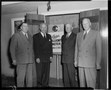 Harold Quinton (second from left) and three other men standing by sign below installed "one millionth" meter in back yard of home