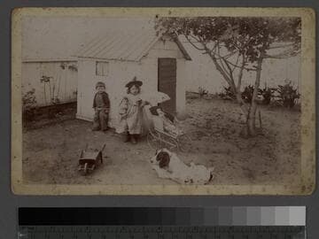 Children in front of playhouse with baby carriage and dog