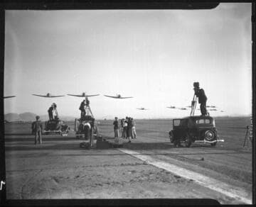 Men filming Army and Navy planes flying over a runway, Riverside. 1937