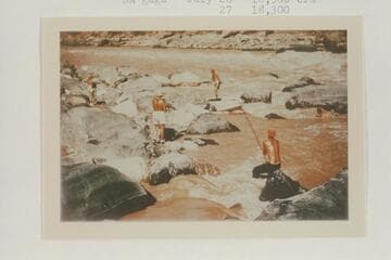 Nevills crew lining Vulcan Rapid.  Nevills stands on the skiff; Milotte tries for a picture from left; Frost strains on the painter; Joe Desloge struggles in the water at right