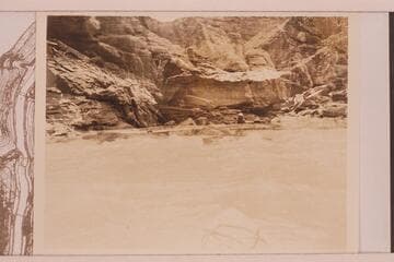 Boat with two men in it in some fast water. It is probably Sheer Wall Rapid with a double exposure at Boulder Narrows
