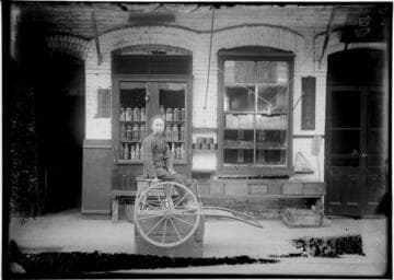 Young man sitting on stool in front of store