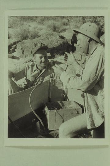 Red Carson gets instruction from Ed Hudson on the operation of the tape recorder carried in the "Esmeralda". Carson flew in by helicopter to the beach at Hance Rapid to meet the motorboat party on June 15, 1950