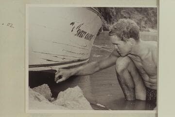 Cooper inspects the damage to the hull of "Sweet Chariot" which occurred in Hance Rapid; Bright Angel Creek