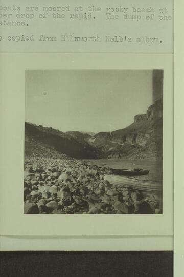 The Kolb boats at Hance Rapid.  The boats are moored at the rocky beach at the lower part of the upper drop of the rapid.  The dump of the Hance Mine shows in the distance