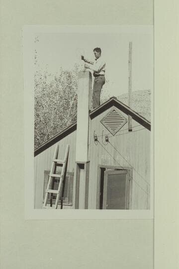 Maxson clears chimney on cabin at Hermit Camp