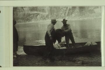 Loading one of Dave Rust's folding canvas boats.  Glen Canyon.  Bert Loper on the left.  Loper on shore and Rust in the boat