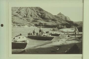 Camp below Temple Butte, Grand Canyon, Mile 66. Rod Sanderson and Dock Marston are in the "Rattlesnake", Garth Marston stands near the boat and Joe Desloge walks on the beach