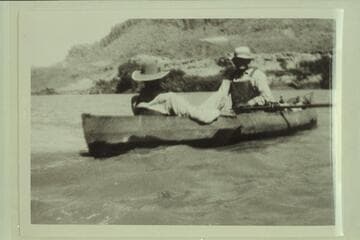 George C. Fraser sitting in the stern of one of Dave Rust's folding canvas boats. Glen Canyon. Bert Loper is at the oars as boatman for Rust