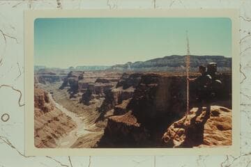 Hildreth posed on Esplanade below Enfilade Point. Mouth of Forster Canyon at lower left