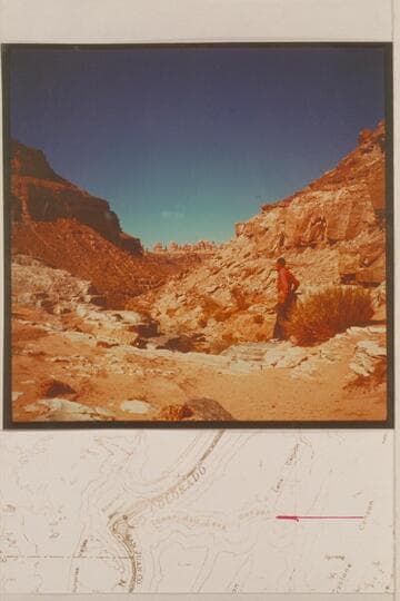 Kent Frost stands at the drop-off of about 30 ft. in the side canyon that enters the Colorado River on the left bank in Cataract Canyon, Mile 213. Standing Rock country in the background which is the opposite side of the Colorado River
