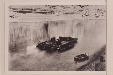 Moving the barge used for the drilling equipment at the lower damsite near Mile 40 in Marble Canyon.  The boat near shore is a 16-ft. Smithcraft.  Copy of print in Rod Sanderson collection