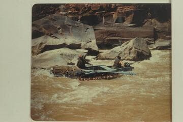 Bus Hatch runs his 10-man inflated boat bow-first and with oars through Triplett Falls while Lloyd Shearer holds the outboard motor clear of the rocks.  The motor was not used in the navigation of the rapid