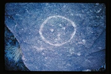 Crude faces and cross atop boulder opposite Range Canyon
