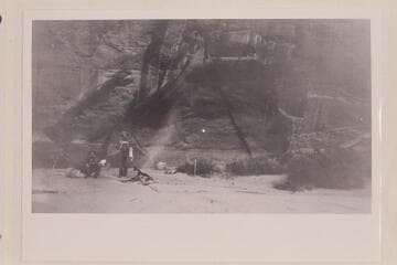Bert Loper's Cave. Loper is standing by the fire. The figure on the bedroll appears to be Christensen. Wright Bar opposite Navajo Creek, Colorado