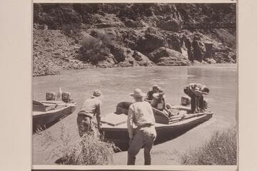 Shoving off from right bank above Bright Angel Creek. The bridge is upper right. Hugh Cutler shoves off while Joe Desloge watches the job. Ballard Atherton is at the controls and Bill Beer at the moorings