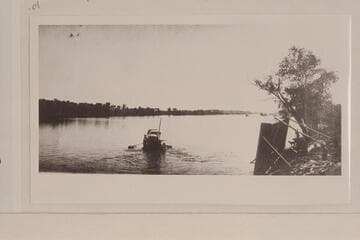 Skiff ferry carrying small buggy at Ehrenberg. The ferry is on its side at the right bank. Copied from print owned by Mrs. Fred V. Kuehn of Quartzite