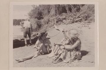 Elgin Pierce prepares the neoprene boat for the Grand Canyon Traverse with Georgie White. Maradel Marston discusses the situation with Margaret Marston and Rosalind Johnson. Below Paria Riffle