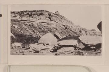 Looking north from a point on the San Juan across from Zahn's Camp.  Moencopie with the De Chelly sandstone lentil in foreground.  Shinarump forms high point.  Note name of Paul Zahn painted on the boulder at center