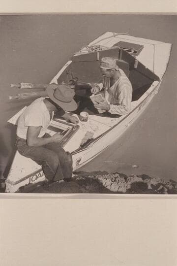 Repairing the sadiron "JOAN" after damage at Rapid #24 in Cataract Canyon.  Nevills wears his cap backwards and his pajama top