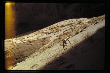 John Harvey Butchart climbing sand dune near mouth of 73