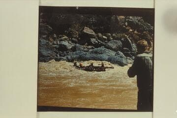 Georgie White's smaller inflated boats in Vulcan Rapid. The two oarsmen seem to be struggling to maintain some sort of control while the passengers sit with backs toward the rapid