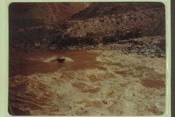 Motorboat driving into head of Lava Falls.  Marston, Desloge, and Taylor in the boat