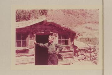 Bert Loper posed by his old cabin in Red Canyon. Photo by a member of the Scout Troop which Loper guided through Glen Canyon