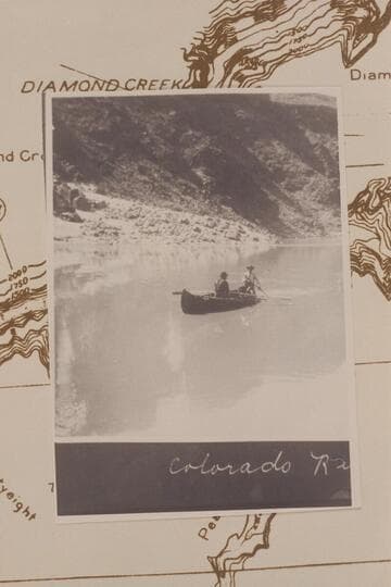 McCuish at the oars and Wilbur steering a folding boat used for prospecting the lower end of the Grand Canyon after an outfit has been lost in the area of Vulcan Rapid