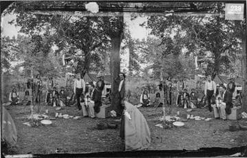 Cheyenne Indians and white men at temporary camp during Grand Council, 1875. G. W. Ingalls seated at right, holding cradle-board