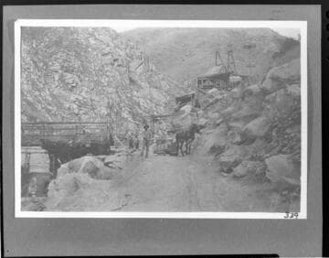 A man standing by a mule hauling a sledge of supplies for the powerhouse construction at Kern River #1 Hydro Plant