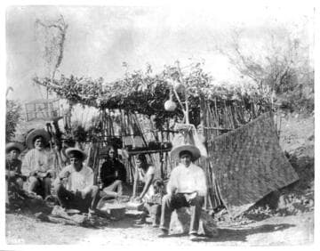 Yaquis at home before a brush hut, Mexico