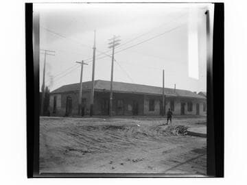Adobe building on street corner with boy standing at right