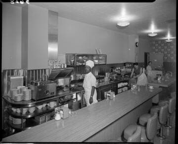 Chef cooking on grill beind lunch counter in a cafe