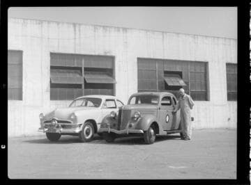 Man standing by two CEP Automobiles at CEP garage