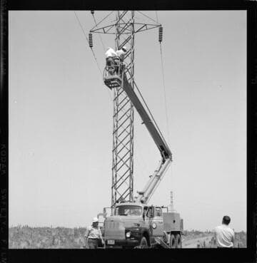 Raising bucket at tower with two men inspecting insulators