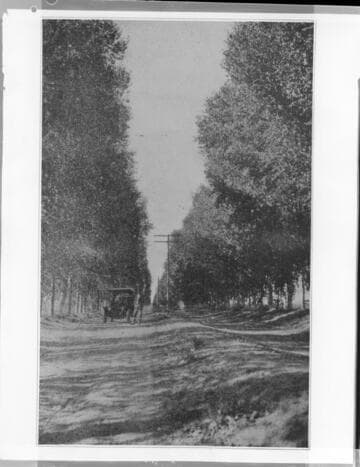 Unpaved road along distribution pole line with old touring car