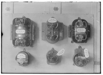 Six electric meters mounted in a group. All are different designs