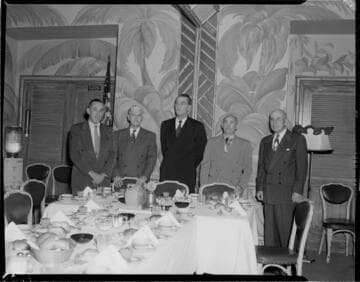 Five men standing at the head of a banquet table