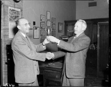 Two men with pipes exchanging trophy