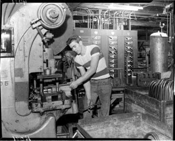 Man bending tubes at a metal brake in a machine shop