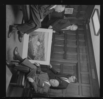 Executives seated in office with artist's drawing of the proposed San Onofre Nuclear Generating Station (SONGS)- Unit 1 project