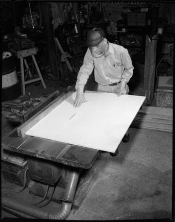 Carpenter cutting a piece of wood on a table saw