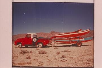 The two glass boats made by Reilly for the traverse of the Grand Canyon, on back of Reilly's truck and at the rim above Badger Creek Rapid