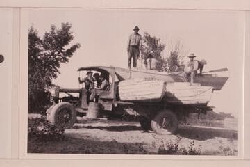 The USGS boats being trucked away from river. Greenriver, Utah. Stoner sits with back to camera. Loper sits facing camera