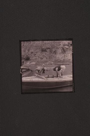 The boats used in the 1954, June traverse of Grand Canyon.  Sanderson has fired up the motors of the "Rattlesnake" while Cutler holds the bow line.  Marston is stowing the lines of the "BOOTOO" while Masland looks on