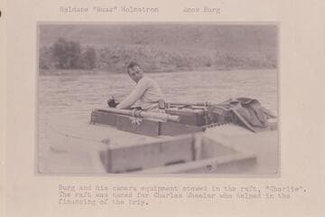 Haldane "Buzz" Holmstrom; Amos Burg.  Burg and his camera equipment stowed in the raft "Charlie."  The raft was named for Charles Wheeler, who helped in the financing of the trip