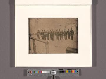 Musical band of 12 members posed outside, with instruments